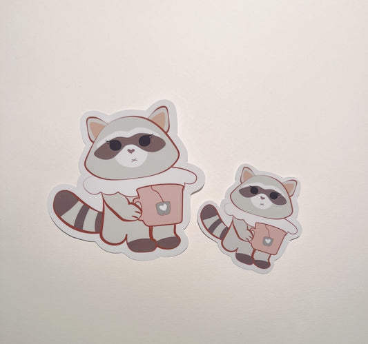 Two raccoon stickers holding a mug, funny stickers,  on a light beige background